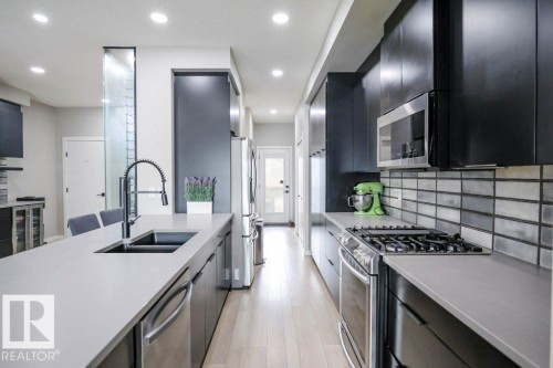 Modern kitchen featuring stainless steel appliances, dark cabinetry, and light-colored countertops - 266 Charlesworth Drive, Edmonton, AB - Indoor Photo Showing Kitchen With Double Sink With Upgraded Kitchen