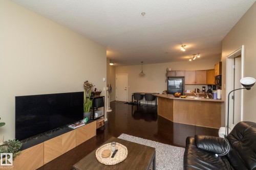 Open-concept living area with dark flooring and light-colored walls - 416 263 Macewan Road, Edmonton, AB - Indoor Photo Showing Other Room