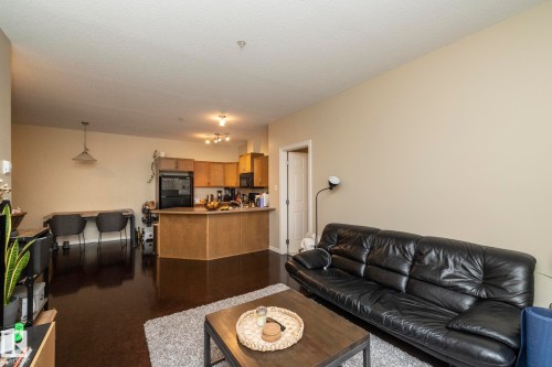 The property features a combined living and kitchen area with dark flooring, light-colored walls, and a visible kitchen island - 416 263 Macewan Road, Edmonton, AB - Indoor Photo Showing Living Room