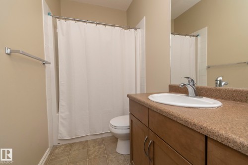 Bathroom featuring a vanity with a countertop sink, a chrome faucet, and a mirror - 416 263 Macewan Road, Edmonton, AB - Indoor Photo Showing Bathroom