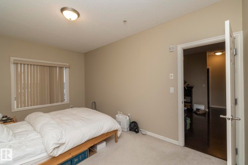 Bedroom featuring light-colored walls, carpeted flooring, and a window with vertical blinds - 416 263 Macewan Road, Edmonton, AB - Indoor Photo Showing Bedroom