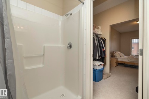 The bathroom features a shower with a white tiled surround and a chrome shower head and faucet - 416 263 Macewan Road, Edmonton, AB - Indoor Photo Showing Bathroom