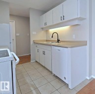 Kitchen featuring white cabinets, white appliances, light countertops, and light tile patterned flooring - 