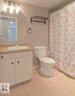Bathroom with vanity, light tile patterned floors, and curtained shower - 
