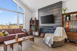 Living area featuring a floor-to-ceiling window, vaulted ceilings, and light wood flooring - 