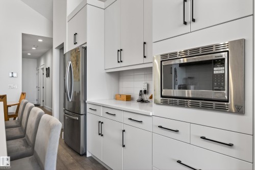 Contemporary kitchen featuring white cabinetry, a stainless steel refrigerator, and a built-in stainless steel microwave - 45 Evermore Crescent, St. Albert, AB - Indoor Photo Showing Kitchen