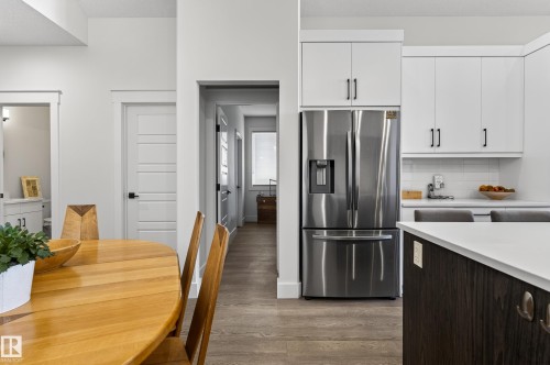 The kitchen features white cabinetry with black hardware, a stainless steel refrigerator, and a white subway tile backsplash - 45 Evermore Crescent, St. Albert, AB - Indoor