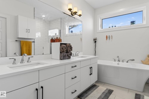 This bathroom features a double vanity with white cabinetry, polished chrome faucets, and a large mirror - 45 Evermore Crescent, St. Albert, AB - Indoor Photo Showing Bathroom