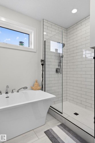 Bathroom featuring a freestanding tub with chrome fixtures, a walk-in shower with subway tile walls, and a window providing natural light - 45 Evermore Crescent, St. Albert, AB - Indoor Photo Showing Bathroom