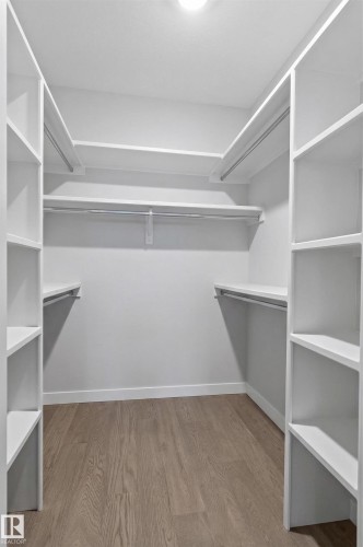 The property features a spacious walk-in closet with built-in shelving, hanging rods, and light wood-style flooring - 45 Evermore Crescent, St. Albert, AB - Indoor With Storage