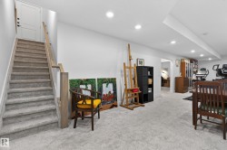 The finished basement offers a spacious carpeted area, recessed lighting, and a well-maintained staircase with a light wood handrail - 