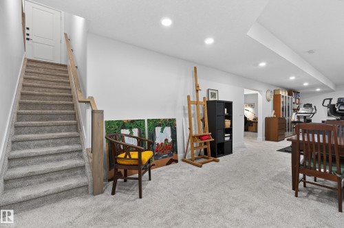 The finished basement offers a spacious carpeted area, recessed lighting, and a well-maintained staircase with a light wood handrail - 45 Evermore Crescent, St. Albert, AB - Indoor Photo Showing Other Room