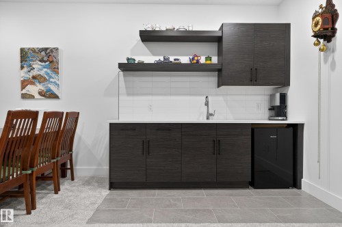 This space features sleek dark cabinetry with a light countertop, a stainless steel sink with a modern faucet, and white subway tile backsplash - 45 Evermore Crescent, St. Albert, AB - Indoor