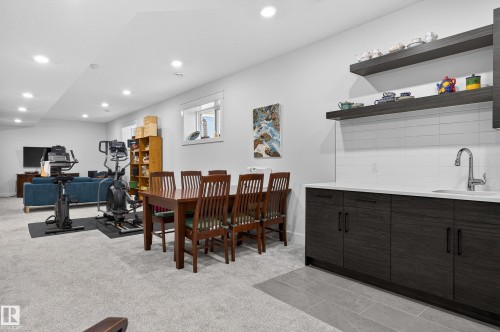 This versatile area features a wet bar with dark wood cabinetry, white countertop, and tiled backsplash - 45 Evermore Crescent, St. Albert, AB - Indoor Photo Showing Dining Room