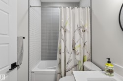 Bathroom with a white bathtub and shower featuring gray and white subway tiling - 