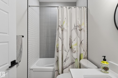 Bathroom with a white bathtub and shower featuring gray and white subway tiling - 45 Evermore Crescent, St. Albert, AB - Indoor Photo Showing Bathroom