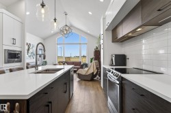 The kitchen features an island with a double sink, white countertops, and dark wood cabinetry - 