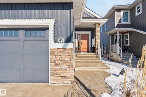 The property features a stone facade accent, a garage with transom windows, and an inviting front entry with an orange door - 45 Evermore Crescent, St. Albert, AB - Outdoor With Facade