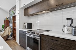 The kitchen features white tile backsplash, a stainless steel range, and rich wood cabinetry with contrasting white upper cabinets - 