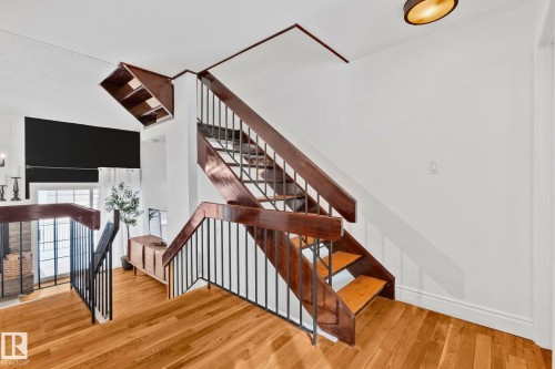 The property features hardwood floors, a staircase with dark wood banisters and black metal spindles, and white walls - 17082 67 Avenue Nw, Edmonton, AB - Indoor Photo Showing Other Room