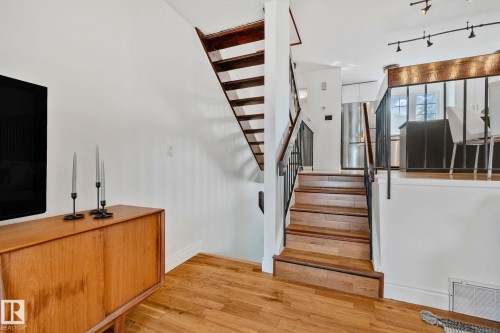 The property features hardwood flooring throughout the main level and a staircase with wooden treads and dark metal railings - 17082 67 Avenue Nw, Edmonton, AB - Indoor Photo Showing Other Room