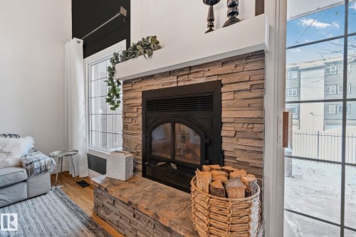 Living area featuring a floor-to-ceiling stone fireplace with a black insert, high ceilings, and light hardwood floors - 17082 67 Avenue Nw, Edmonton, AB - Indoor Photo Showing Living Room With Fireplace