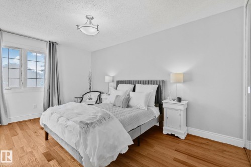 This bedroom features hardwood floors, a window with views of mountains, and light grey walls - 17082 67 Avenue Nw, Edmonton, AB - Indoor Photo Showing Bedroom