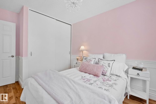 This room features hardwood floors, a white panel door, and a white sliding door closet - 17082 67 Avenue Nw, Edmonton, AB - Indoor Photo Showing Bedroom