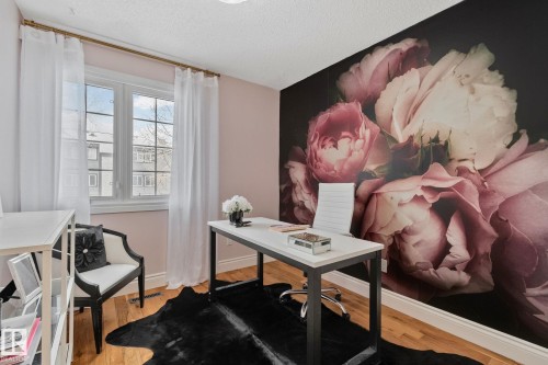 This space features hardwood floors, a large window with white curtains, and a distinctive floral accent wall - 17082 67 Avenue Nw, Edmonton, AB - Indoor Photo Showing Office