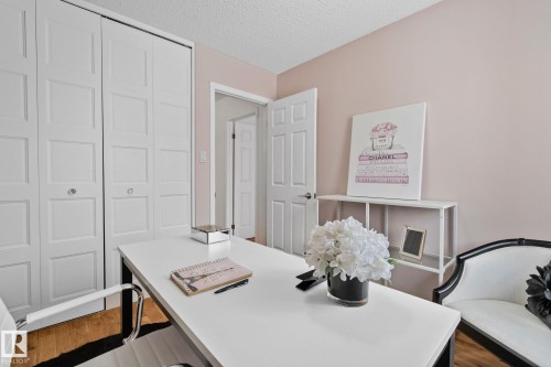 This room features light-colored walls, white bi-fold doors, and a white desk with a chair - 17082 67 Avenue Nw, Edmonton, AB - Indoor