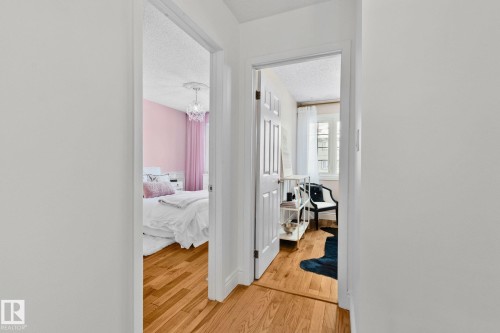 The interior features light wood flooring and white walls, with doorways leading into rooms with distinct wall colors - 17082 67 Avenue Nw, Edmonton, AB - Indoor Photo Showing Other Room