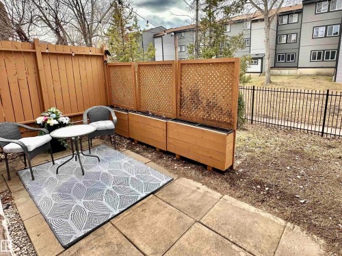 This property features a paved patio area with a privacy fence, raised wooden planters, and string lighting - 17082 67 Avenue Nw, Edmonton, AB - Outdoor