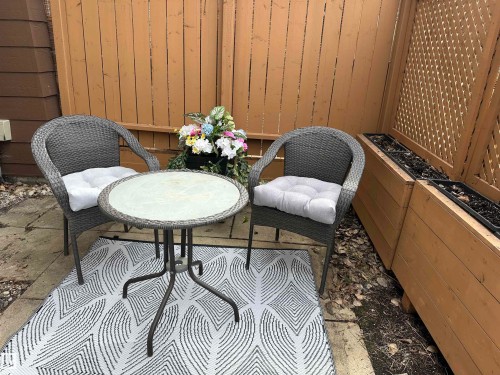 The property includes a paved patio area, featuring a privacy fence and built-in planters - 17082 67 Avenue Nw, Edmonton, AB - Outdoor With Deck Patio Veranda With Exterior