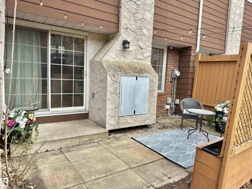 The property features a patio area with concrete pavers, a privacy screen, and a sliding glass door - 17082 67 Avenue Nw, Edmonton, AB - Outdoor With Exterior