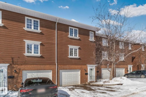 The property features a brown wood-paneled facade with white-framed windows and a brick foundation, complemented by an integrated garage - 17082 67 Avenue Nw, Edmonton, AB - Outdoor