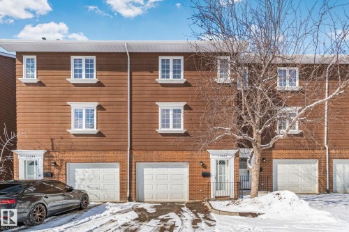The property features a brick and siding exterior, white-framed windows, and an integrated garage - 17082 67 Avenue Nw, Edmonton, AB - Outdoor With Facade