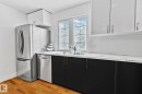 The kitchen features stainless steel appliances, a double sink, black lower cabinetry, white upper cabinetry, and a white subway tile backsplash - 17082 67 Avenue Nw, Edmonton, AB  - Indoor Photo Showing Kitchen With Double Sink 
