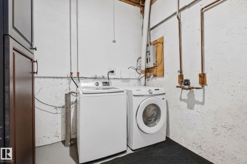 Laundry area featuring a top-loading washing machine, a front-loading washing machine, and dark cabinetry - 17082 67 Avenue Nw, Edmonton, AB - Indoor Photo Showing Laundry Room