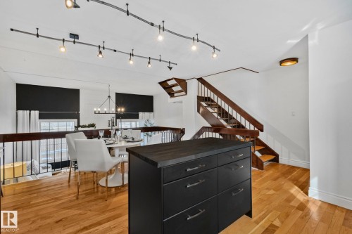 The open concept living area features hardwood floors, track lighting, and a dark wood staircase - 17082 67 Avenue Nw, Edmonton, AB - Indoor