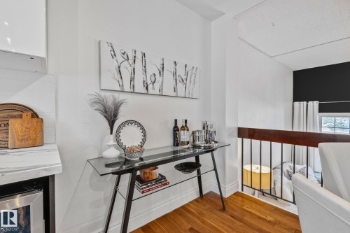 This property features hardwood floors, a white interior color palette, and a dark wood and metal railing - 17082 67 Avenue Nw, Edmonton, AB - Indoor