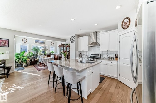 The kitchen features white cabinetry, a stainless steel range hood, a tiled backsplash, and an island with a light-colored countertop - 22407 99 Avenue, Edmonton, AB - Indoor