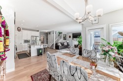 This open-concept living space features light-toned flooring, a dining area with a modern chandelier, and access to an outdoor area through a glass-paneled door - 