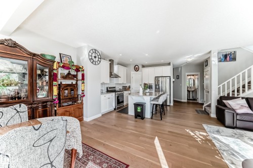 The property features an open-concept living space with hardwood flooring, a modern kitchen with white cabinetry and stainless steel appliances, and a central island with bar seating - 22407 99 Avenue, Edmonton, AB - Indoor