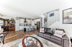 The open concept living area features light wood flooring and light-colored walls, providing an expansive feel - 