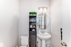 The bathroom features a pedestal sink with a mirror and a wall-mounted light fixture - 