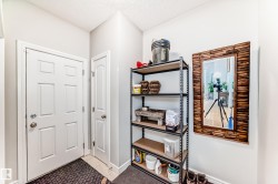 This entryway features a white paneled door, light gray walls, and a decorative mirror with a wooden frame - 