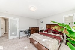 This bedroom features light-colored carpeted flooring, a solid wood bed frame, and a chest of drawers - 