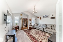 Living room featuring vaulted ceilings, light grey walls, and windows with blinds - 
