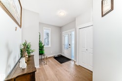 The entrance features a hardwood floor, a white front door with decorative glass panels, and a closet with white bi-fold doors - 