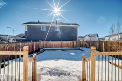 The property features a fenced backyard with a snow-covered lawn and a wooden deck with metal balusters - 